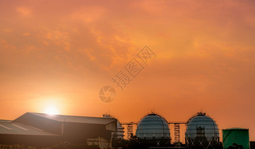 生产黄昏LNG或液化天然气储油罐红日落和橙色天石油炼厂地面储罐的球状气天然贮存工业公司危机图片