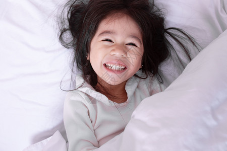 情绪化的早上躺在床柔软枕头欢笑着开心快乐的亚洲小孩最喜悦的一景亚洲人们图片