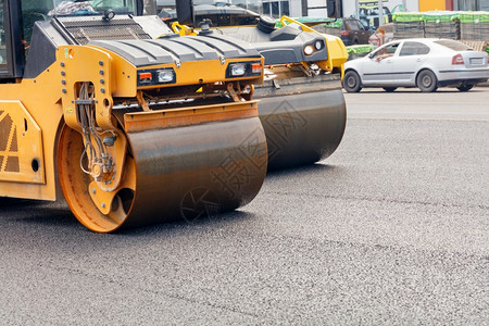 重点商业大量的黄色道路振动滚筒的金属圆柱将公路建筑工地上的新沥青紧绑在城市街道上的背景之下在城市街道背景上压着新沥青的道路滚车在图片