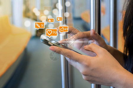 在Skytrain铁路或城市旅行地铁的社交网络概念中女使用智能手机为社交网路媒体提供类似爱评论人和fovorite图标的数量电话图片