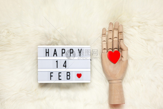 假期人类Trendy木人手模型握着红心灯盒上面刻着快乐14FEB的首字母快乐14FEB这意味着情人节在白毛地毯上子图片