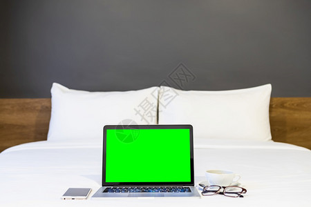 房间设计师自在旅馆卧室内背景工作和业余度假期旅行时带空白屏幕的手提式电脑智能手机咖啡杯和眼镜贴在白色床上装饰的品上图片