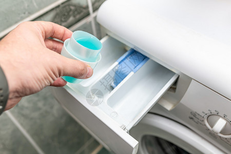 效用家庭填充男手把洗衣涤剂倒进机然后在涤剂上浇水图片