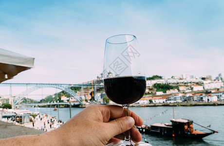 廷托酒精垂直的葡萄牙波尔图杜罗河上的手拿红酒俯瞰CaisdaRibeira和PontedeDomLuisI葡萄牙波尔图的手拿着红图片
