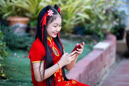红色的幸福人们身着传统红潮相香装饰的可爱亚洲小女孩在神庙新年节举行自拍带智能手机的新年节时图片