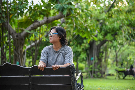 优雅天户外坐在绿公园的亚洲女人坐着放松在公园里的亚洲女人坐着放松在公园里休息时戴着眼镜树叶高清图片素材