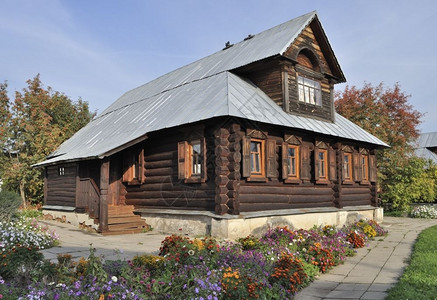 手工制作的村庄俄罗斯苏兹达尔波克罗夫斯基修道院美丽的棕色木屋和花床灰莓图片