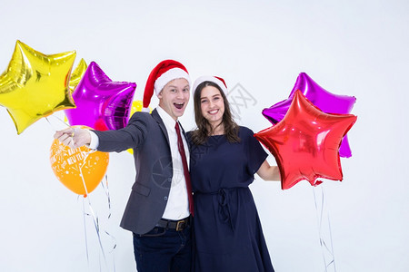 乐趣庆典套装一对工作年龄男子在20年的标签和彩色气球上手握着一件商业西装满面快乐脸孔的热彩气球在圣诞节期间庆祝白色背景的新派对图片