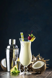 由一片菠萝和樱桃装饰的以黑木为背景的鸡尾酒在黑暗木质背景上供奉而成传统的服务桌子图片
