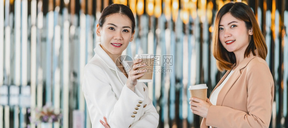 合伙团队作成功在现代办公室或合用空间咖啡休息放松和谈话商业人际伙伴关系概念期间发言的两名亚洲女商人的Banner网页或封面样板模图片