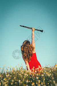 单簧管演奏家吹自然穿着红裙子的女人在田地里举着单簧管图片