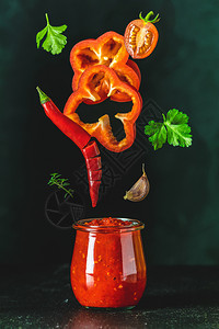 传统的冷冻在空气中自制DIY天然罐装热番茄酱土豆油玻璃罐里有辣椒或Adjika放在木桌上配有飞动成份选择地聚焦成熟木制的图片