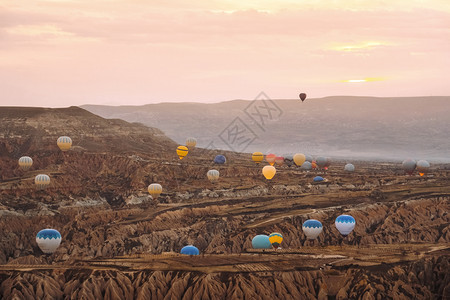 游客空气地标在卡帕多西亚山谷上空飞行的多彩热气球在土耳其流行旅目的地Capapadocia日出时飞过山谷图片