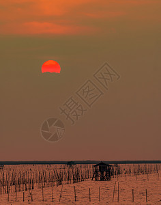 黄昏时海面上美丽的夕阳天空光被日落时的乌云遮蔽在泰国海岸钓鱼的渔夫小屋黄昏时席丽休埃特海景和沿小屋轮廓洋日出图片