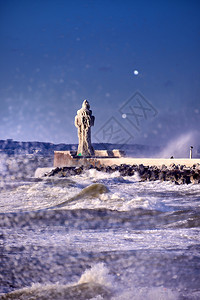 寒冷的灯塔和码头在暴风寒冬日蓝色的天戏剧图片