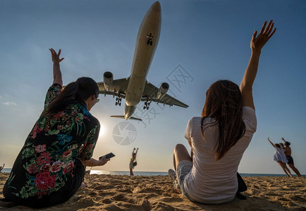 两名旅行女子的场景展示手和滑稽与飞机搭乘在泰国普吉际机场附近的海滨距离降落泰有趣的自然海洋图片