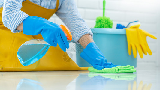 家庭主妇服务地面身戴橡皮手套布清洁或在家施用地板护理和清洁工家务管理概念的女家佣佩戴橡胶手套图片