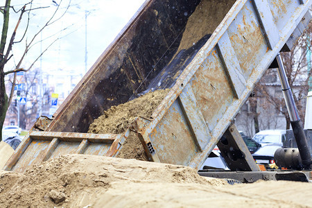 移动行业黄色的在一座城市街道的建筑工地一辆货运卡车倾弃沙从卡车上倒出图片