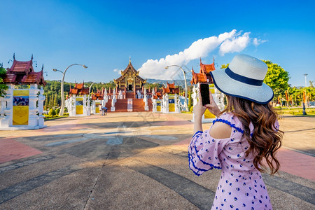 文化女使用手机在泰国清迈的皇家花旗牌Tratchaphruek拍摄HokhamLuang北海风格的照片拉查普鲁克建造图片