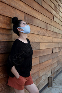 紧的亚洲年轻妇女戴上医疗面具以保护免受空气呼吸道疾病如长墙旧木本底的流感19PM25粉尘和烟雾打喷嚏美丽一种图片