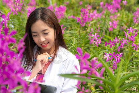 科学家花园快乐的研究员植物兰花身戴白帽子手拿着笔和记本作研究录丰富多彩的图片
