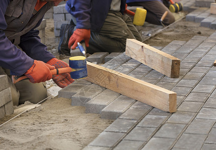 工具修理人用特殊的锤子铺的板根据在人行道上铺瓷砖的紧张线水平整石板工人把瓷砖放在钢丝上对齐工作场所图片