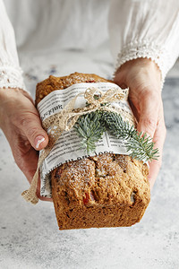 喜庆的德语斯托伦是坚果香料干或罐头水的面包涂有糖粉和它是在圣诞节期间女手中食用鸡尾酒的传统德国面包木制的图片