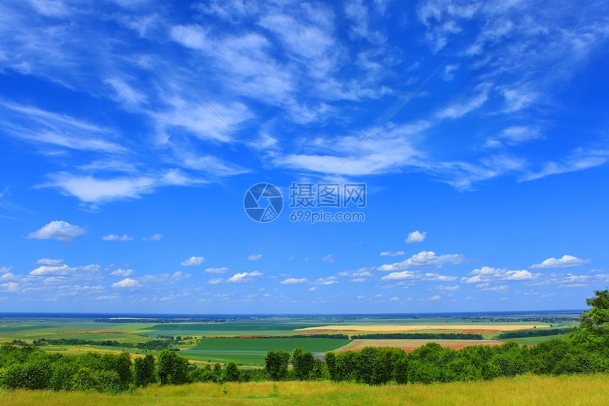 超过沉降风景优美在丽的农村景观上画出夏月的云彩景色草坪和林地田野草原森林道路村庄和远方背景阳光温暖的天气住区上树木图片