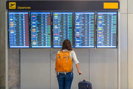 在现代机场旅行和运输概念的飞行信息屏幕登入飞行信息屏幕时背着行李站在飞板上办理登机手续的亚洲女背包车或旅行者面的携带李妇女背包车图片