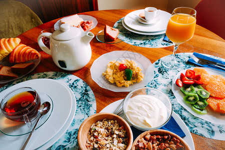 食物早餐桌包括谷类食品酸奶炒鸡蛋水果羊角面包和茶咖啡橙汁等饮料早餐桌包括谷类食品羊角面包和茶等饮料咖啡和橙汁烹饪有机的图片