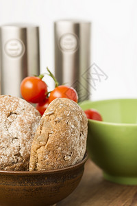 新鲜烘烤的棕色全草干面包卷新鲜烘烤的棕色全谷物面包卷在厨房的碗里用包装着一盒樱桃西红柿准备一份健康的三明治点心饮食新鲜的小麦图片
