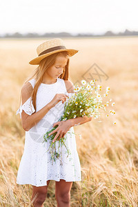 花朵童年可爱的麦田里快乐孩子戴着草帽的白色连衣裙漂亮女孩手里拿着一束洋甘菊麦田里的快乐孩子戴着草帽的白色连衣裙漂亮女孩手里拿着成图片