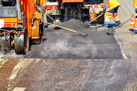 维护机器车轮一组身穿保护橙色制服的公路工人使用铲子平面和小型道路设备修理段复制空间A组道路工人使用手具和道路设备维修段部分公1个图片