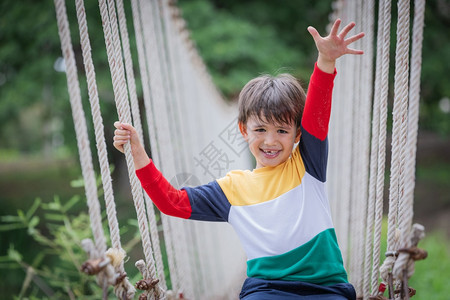 走肾上腺素一个男孩穿着亮色衣服独自坐在绳桥上冒险公园的极端运动中独坐步行图片