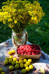 木头素食主义者甜的木制桌边篮子里新鲜甜果酱莓与黄樱桃羽和梅一起躺在木制桌边的篮子里美丽的日落光照亮了图片
