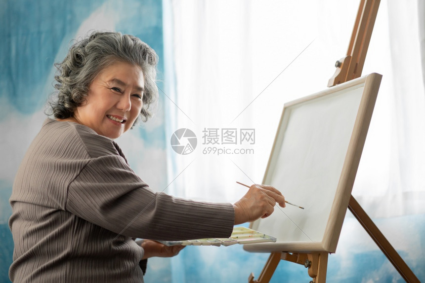 人帆布结合在节假日的室内画布上微笑快乐的亚洲老年妇女油画艺术家穿散衣的高级女妇手持油漆笔纸和彩色调盘子研究艺术水彩和丙烯颜色观看图片