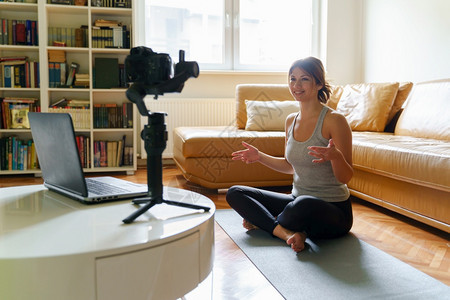 视频博客网络年轻的caucasiansian年轻女在家中做瑜伽美丽的教官在公寓里授线课程培训白天或早晨当着摄影机和笔记本电脑的面图片