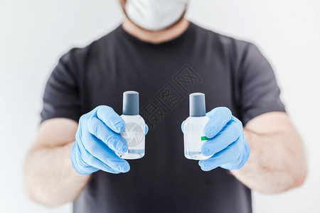 清洁剂保持在科罗纳COVID19传染病卫生和安全措施期间身戴乳胶医疗手套和保护面罩的男子手中有洗涤剂卫生清洁酒精凝胶瓶曲线图片