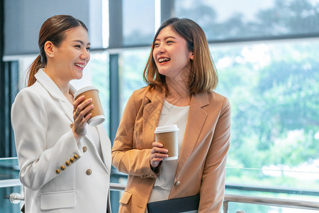 幸福人们合伙在现代办公室或合用空间的咖啡休息期有两名亚洲女商人在咖啡休息下班后放松和谈话商业人员伙伴关系概念时发言图片