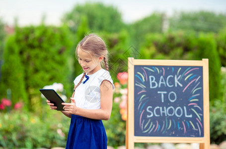 课堂黑色的现代快乐小女学生有笔记本电脑背景在黑板上回校外户学快乐的小女学生在户外有一个黑板图片