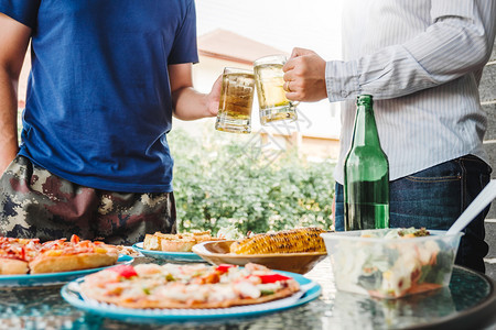 朋友们在享受家庭派对的同时愉快地喝啤酒与烧烤猪肉和蔬菜吉他饮料图片