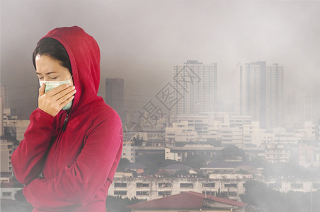 亚洲人妇女有流感喷嚏妇女穿着粉红色的冬季衣着戴面罩在她的鼻子上面对曼谷市覆盖有毒尘埃的感寒冷和流健康概念身穿针粉色的冬季衣服对曼图片