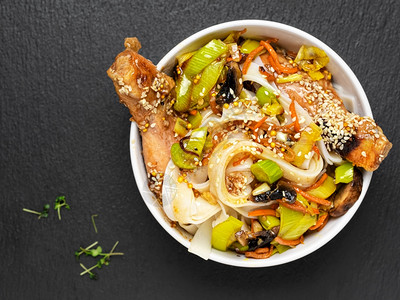 健康一种亚洲风味面条配蔬菜鸡肉和照烧酱顶视图碗面位于黑石背景上午餐鸡肉面条蔬菜香料和微绿色亚洲风味面条配蔬菜鸡肉和照烧酱新鲜的图片
