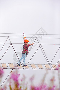 最佳RosaKhutor山顶的绳桥俄罗斯小勇敢的孩子在一座吊桥上横跨山脉的深渊俄罗斯RosaKhutor山顶的绳桥罗扎波利亚纳图片