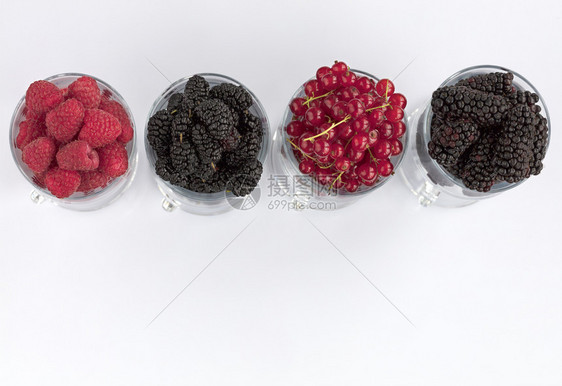 为了黑莓大和红沙律被倒入透明的拿铁杯中在光背景上排成一高键Raspberry的图像大黑莓和红草原以光背景置于清晰的玻璃里一个黑色图片