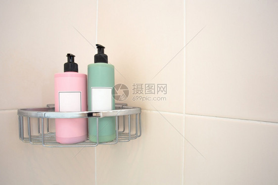 两台彩色糊涂肥皂撒布机放在压砖墙的淋浴架上现代设计装有空白标签间用于文本两个彩色覆漆肥皂撒布机安装在隔板墙上的淋浴架现代设计贴空图片