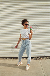 奶油穿着白色T恤衫和轻牛仔裤的年美籍非裔女孩在阳光日吃冰淇淋有选择地关注小重点领域食物美丽的图片