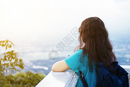 独自的欣赏草地亚洲年轻女子蓝礼服携带便袋旅行者仰慕城市风景山地背观赏城市色图片