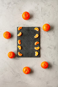 瘦身核有机的橘子亮光和多汁的碎片埋在一块灰色板上周围环绕着整片橙红色橘子位于灰混凝土底部复制空间垂直图像浅亮和多汁的曼达林片落在背景图片