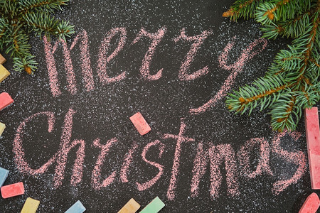 水平的邀请问候圣诞背景或明信片圣诞快乐字样带有粉笔黑板布局用于礼物并云杉树枝装饰从上方查看图片